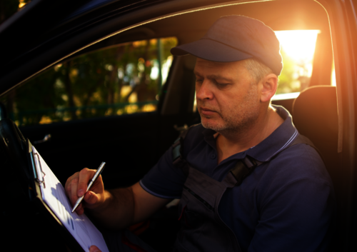 Techniker sitzt im Auto und hakt auf einer Liste Dinge ab, im Rahmen einer Installation einer Wallbox.