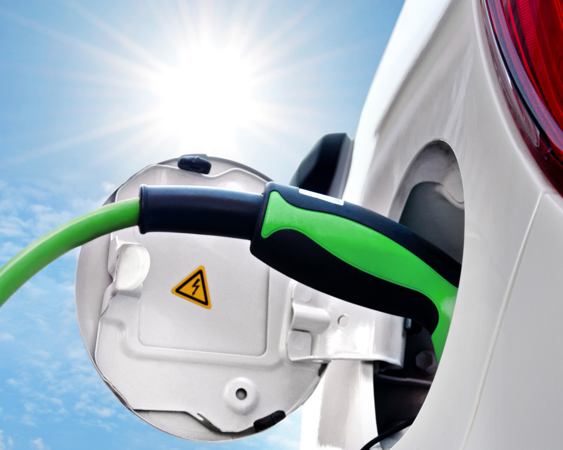 Elektroauto ist an eine Ladestation angeschlossen und wird aufgeladen, während die Sonne im Hintergrund strahlt – ein Symbol für die Kombination von Solarpower mit einer Wallbox.