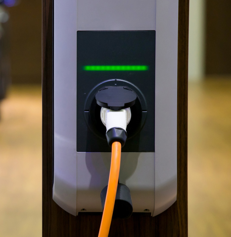 Wallbox-Ladestation mit eingestecktem Kabel, das durch grünes Licht signalisiert, dass sie betriebsbereit ist.